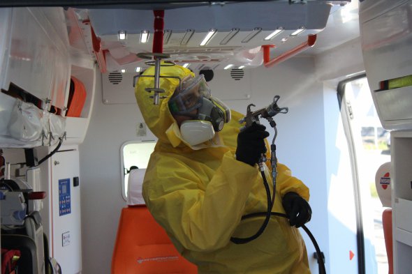 Співробітник компанії обробляє салон медичного автомобіля іноваційним деззасобом на основі діоксиду титану