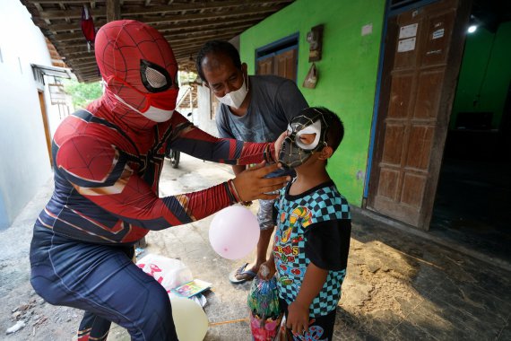 40-річний чоловік в костюмі супергероя розважає хлопчика, мати якого померла від короновірусної хвороби (COVID-19), в масці Людини-павука в Сукохарджо, провінція Центральна Ява, Індонезія