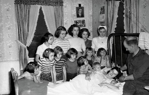 Американка 39-річна Леслі Брукс лежить із новонародженим сином Бенджаміном вдома в американському місті Піттсфілд, 14 жовтня 1954-го. Поряд – чоловік та їхні 13 доньок. Найстаршій – 16 років, а найменшій – 18 місяців. Мали титул ”Родина, в якій народжуються тільки дівчатка”, який з появою хлопчика місцева влада передала іншій сім’ї. Батько сказав журналістам, що більше дітей у них не буде