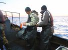 Рибалки готуються діставати з води сітки - допомагають один одному надягати прогумовані фартуки