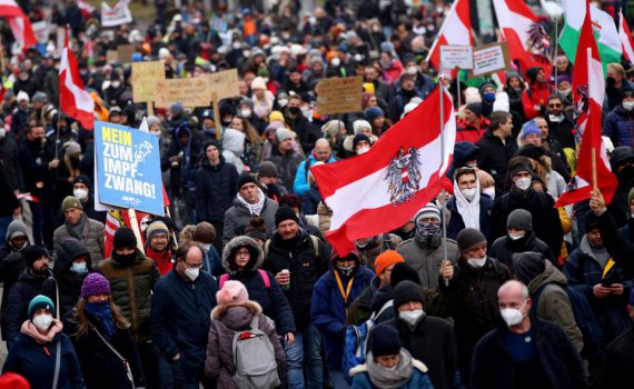 Демонстранты держат флаги и плакаты во время марша протеста против ограничений из-за коронавируса и обязательной вакцинации в Вене, 4 декабря 