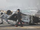Мужчина проходит мимо машины, сгоревшей во время акций протеста в Алматы