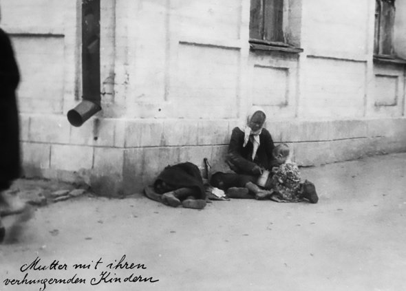 Жінка зі своїми голодними дітьми сидить на вулиці в Харкові, 1933 рік