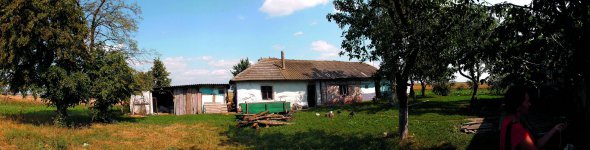 Сарай стоїть навпроти хати Ольги Мороз на хуторі Мартинівка Тернопільської області. Жінка тримає птицю. Кілька років тому в неї вкрали дві корови